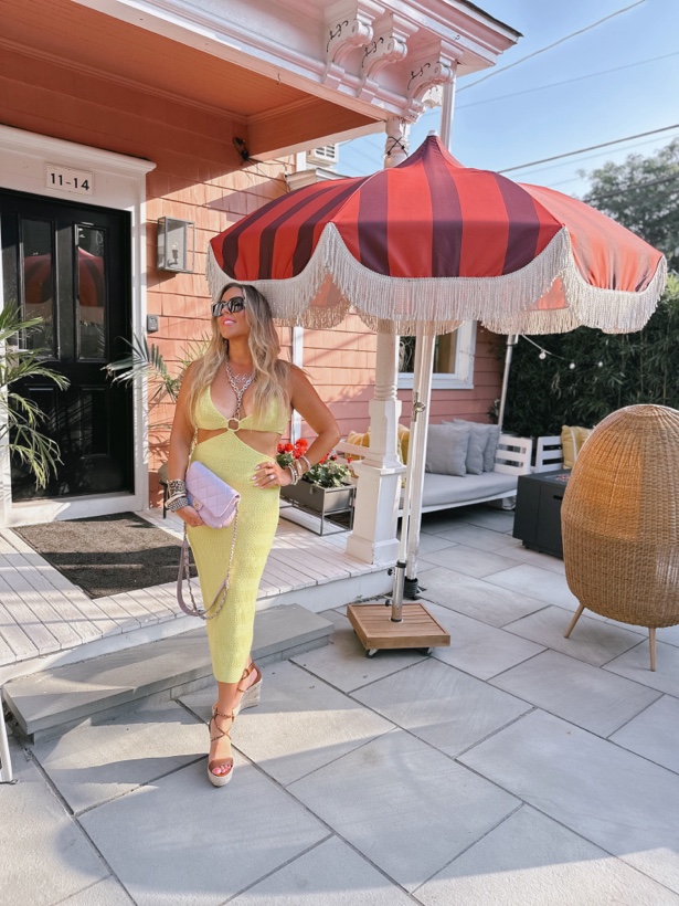 Ashleigh Malangone in a yellow dress under a striped umbrella